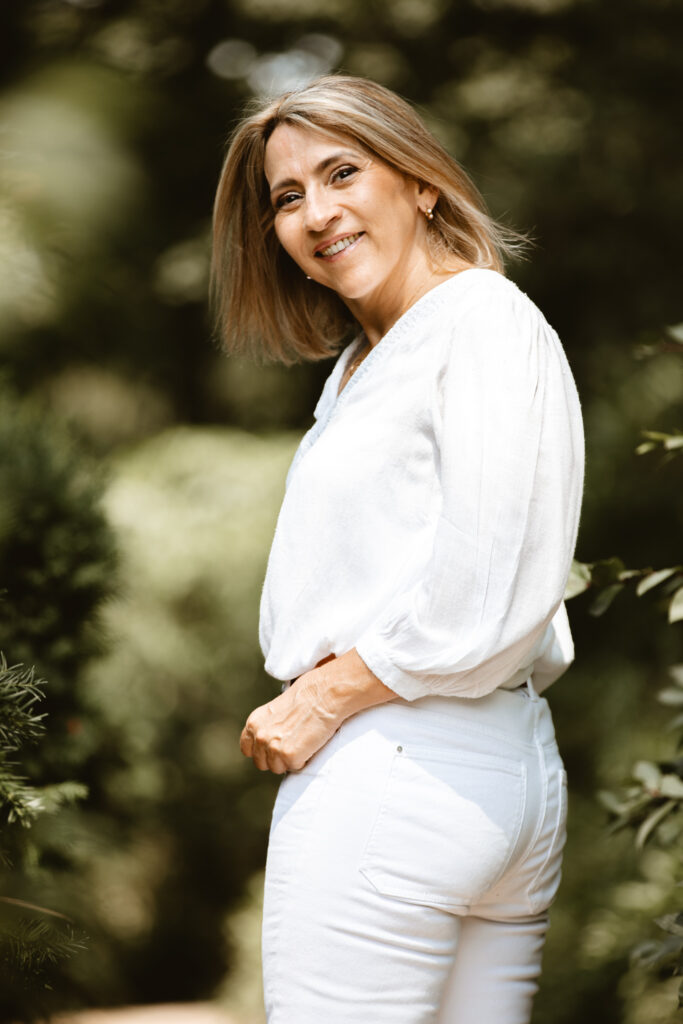 femme age mur qui se balade dans un parc et qui se retourne et sourit à la photographe