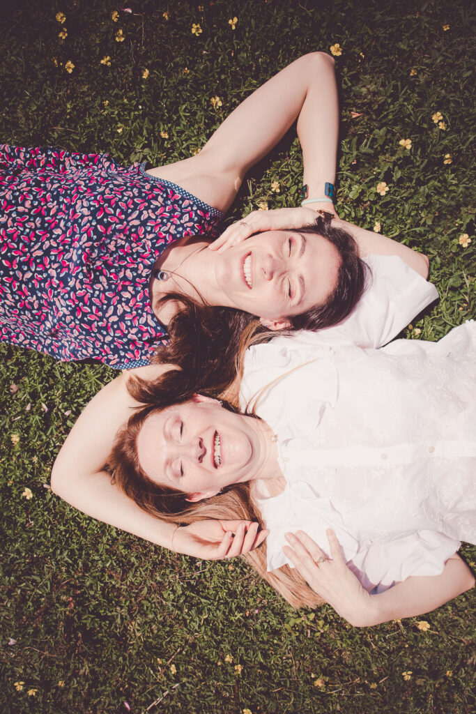 mere et fille allongées dans l'herbe et les feuilles, se tenant l'une et l'autre